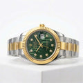 Luxury watch with green dial and gold and silver band on a white background