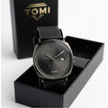 Black watch with leather strap in a TOMI box on a white background